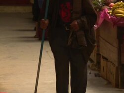 "Pan up from boots of elderly man to face, walking with a stick past colourful market stalls, Chachapoyas market, Chachapoyas, Peru [PerÃƒÂº]" Stock Footage