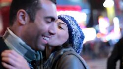 Young woman kisses boyfriend on cheek and laughs beneath the lights of Times Square Stock Footage