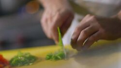 Skilled chef chops green bell peppers on kitchen table in restaurant Stock Footage