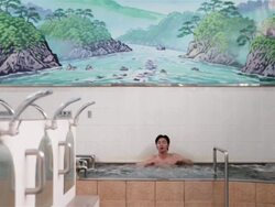 WS, TD A man rubs his face sitting in a traditional Japanese public bath house or sento / Tokyo, Japan Stock Footage