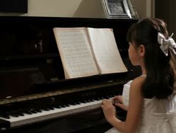 MS Rear view of girl wearing white dress, playing piano / China Stock Footage