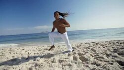Capoeira master throws punch at camera and spins in the sand on Ipanema Beach Stock Footage
