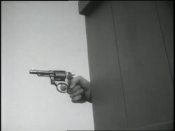 An F.B.I. agent shoots a pistol from behind a wall. News Clip