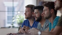 Guys sitting on couch playing video games and cheering Stock Footage