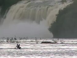 WS Two boys sitting in canoe and huge waterfall in background / Venezuela Stock Footage