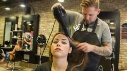 Male Hair stylist drying a female clients hair Stock Footage