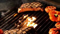 Steaks and vegetables sizzle on a grill. Stock Footage