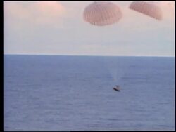 wide shot AERIAL of space capsule with parachutes splashing down / Apollo 13 Stock Footage
