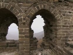 A portion of the Great Wall of China, then panning to a mountain and a snow-covered path.  Stock Footage
