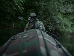 MS Shot of Force Recon soldiers in camouflaged folding boat moving in river during reconnaissance mission in jungle with light machine gun in his arms / Swamp, Virginia, United States Stock Footage
