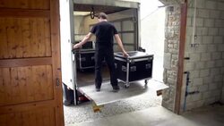 Sound technician unloads flightcase and sound equipment from truck Stock Footage