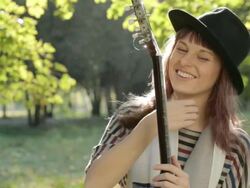 Young woman flirting in park, holding guitar, smiling, posing outdoors. Stock Footage