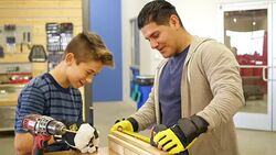 Mid adult Hispanic teacher helps preteen student measure boards at community workshop day camp Stock Footage