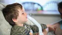 A mother comforts her little boy as he breathes near a nebulizer to inhale medicine. Stock Footage