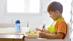 Little boy eating lunch by the table and watching video Stock Footage