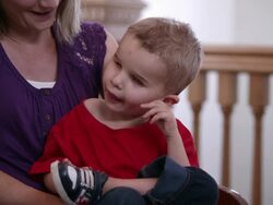 'Tilt up to Close Up of a blond, blind male toldder in his mother's lap.' Stock Footage