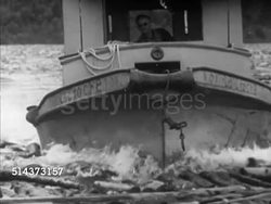 1952: CANADA: LUMBER INDUSTRY: HA WS Small boat moving through floating logs, LA Boat moving down log filled river, OUT OF FOCUS CLOSE, VS Lumbermen, log drivers w/ poles on top of floating logs, redirecting, running over log jam. Pulp, paper, w Instructional Video