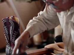 MS TD TU boot maker using tool to stretch leather and place tacks in sole of cowboy boot Stock Footage