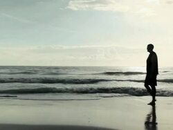 Silhouette of man walking across sandy beach Stock Footage