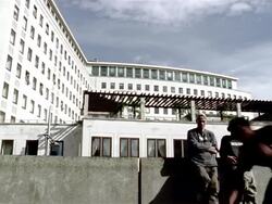 Slow motion wide shot freerunner doing flip as two others stand and watch Stock Footage