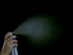 High Speed Aerosol, hand holding can, sprays fine white mist into air against black background Stock Footage