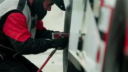 Pit-crew tightens race-car lug-nuts and lowers jack Stock Footage