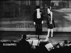 1920s: VAUDEVILLE: Flyer page from Palace Theatre w/ dates & performers. ACTS: WS Male & female walking onto stage, MS both standing in front of orchestra pit at footlights. Two tap dancing men (one seated). VS Male performing w/ large rings. Instructional Video
