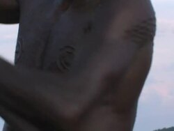 Medium Close Up hand-held - A man covered with scarring tattoos rows a boat. / Papua New Guinea Stock Footage