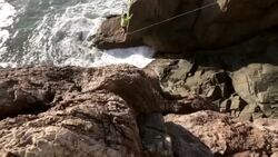 Man traverses highline stretched above sea below Stock Footage