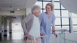 Nurse guiding patient with walker in hospital corridor Stock Footage