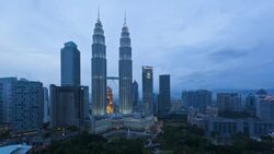 Lights illuminate the Petronas Twin Towers as day turns to night in Kuala Lumpur, Malaysia. Stock Footage