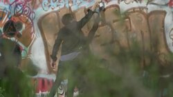 Young man tags graffiti wall with spray paint Stock Footage