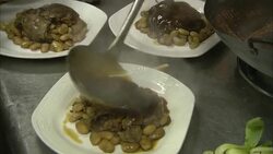 Chefs ladle food onto plates in a restaurant kitchen. Stock Footage