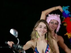 MS Two females modelling in bikinis on motorcycle with facial jewelry and feather boa moving with rythmn / Montezuma, Punteranes, Costa Rica Stock Footage