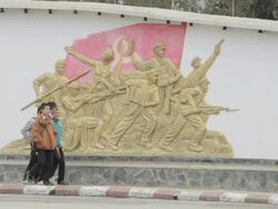 WS PAN boys walking past mural / Sam Nuea, Laos Stock Footage