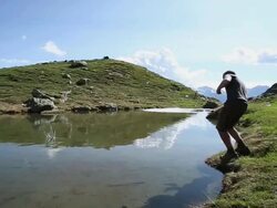 Young man skips stone across mountain lake Stock Footage