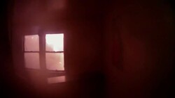 Slow Motion POV, firefighter sprays water through second story window to fire on roof of house Stock Footage