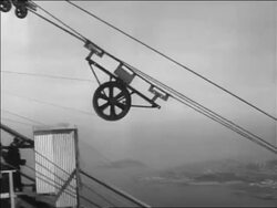 B/W 1936 tracking shot wheel sliding down cable on Golden Gate Bridge under construction / SF / news. Stock Footage