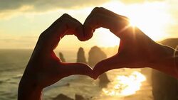 Person frames Twelve Apostles at sunset into heart shape Stock Footage