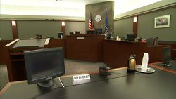 A computer and coffee carafe occupy the defendant's table in a courtroom. Stock Footage