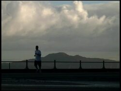 Runner Silhouetted In Front of Perfect Volcanic Island. Stock Footage