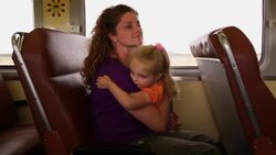 Mother cradles young daughter in her arms as they travel on a train Stock Footage