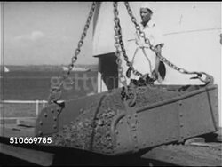1953: GOA, INDIA: MORMUGAO PORT: WS Crane lowering open container of ore onto ship, Indian men working crane, unhooking container bed chain, dumping container into cargo hold.   Inexpensive product, export, exporting. Instructional Video