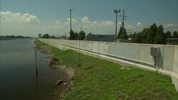 A levee wall separates a canal from a residential area. Stock Footage