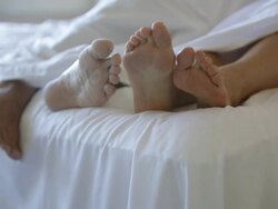  PAN Feet of two people in hotel bed / Stowe, Vermont, United States Stock Footage
