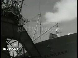1949: SWEDEN EXPORT: MS Swedish dock worker, crane hoisting packaged lumber. LA WS Crane loading lumber onto ship deck. WS Worker securing chains around wooden blocks. WS Crane loading blocks. VS Pier, Russian ship in dock. MS Hoisting steel bars. Instructional Video