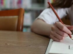 Chinese female student writing on notebook in library,real time. Stock Footage