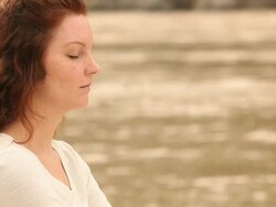 Young woman practicing yoga at riverside, Ganges River, Rishikesh, Uttarakhand, India Stock Footage