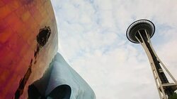 The Space Needle with the Experience Music Project museum and trees,clouds with sun behind it. Stock Footage