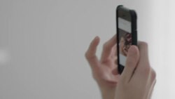 Young man in bed with girlfriend looks at photo on smartphone and laughs Stock Footage